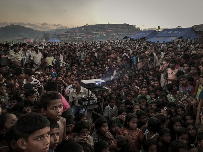 Rohingya children watching an awarness film about health and sanitation near Tangkhali refugee camp in Ukhiya. More than 655,000 Rohingya who have fled to Bangladesh since the Myanmar military began its crackdown in late August.Almost 60 per cent of the refugees are children. Many have become separated from their families or fled on their own. Women and children fleeing from Myanmar’s Rakhine State into Bangladesh have reported experiencing or witnessing brutal acts of violence – accounts which point to grave human rights violations. Around 380,000 are minors, according to Save the Children, the international aid organization. At least 30 percent of the refugee population is younger than 5 And the threat to young lives doesn’t end when they cross the border. Unicef says that 7 percent of children in the camps are suffering from severe acute malnutrition, a condition from which they will die unless they get proper care. That figure is three times higher than in other recent humanitarian emergencies. Outbreaks of communicable diseases, such as measles and diphthera are sweeping through the overcrowded camps, which, with the recent influx, now house more than 800,000 Rohingya. Other dangers lurk in the disorderly setting of the camps, including traffickers and others looking to exploit and abuse the young and vulnerable. hundreds of thousands of Rohingya children will grow up both stateless and homeless an untethered life of displacement that bodes ill for a people already wounded by decades of military persecution in Rakhine State.